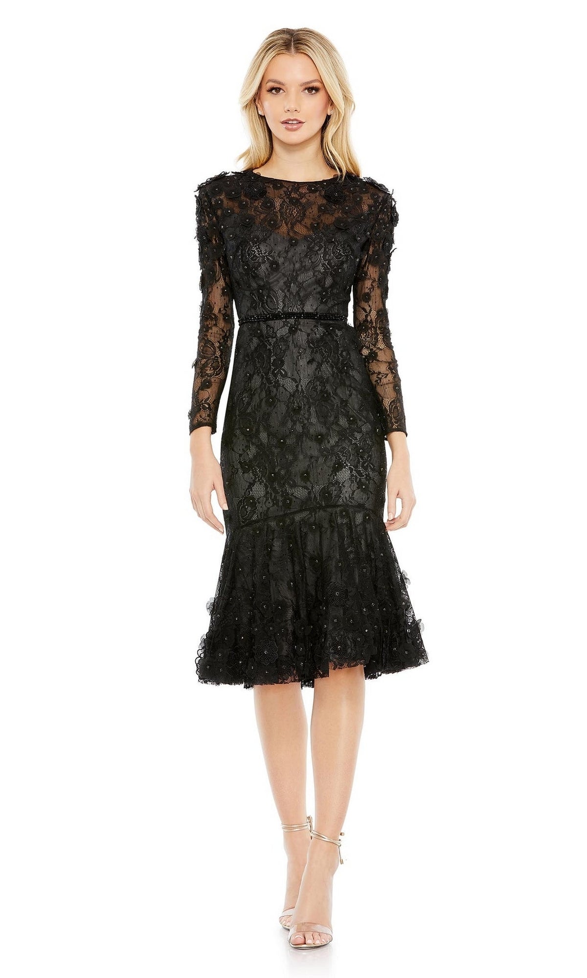 A woman wears the Mac Duggal 67703 knee-length black party dress with long sleeves, a fitted waist, sheer details, flared hem, and pairs it with strappy heels.